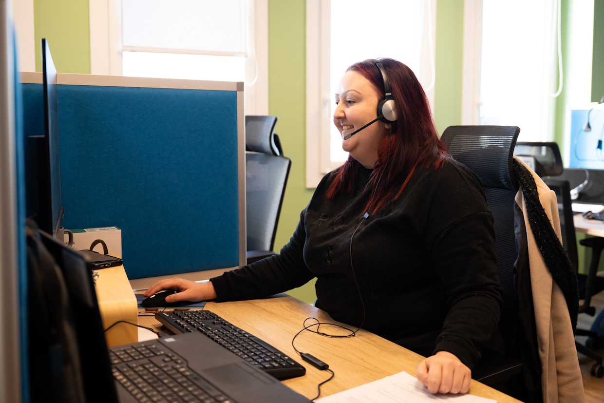 Femme souriante travaillant au casque dans un bureau.